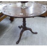 A George III mahogany tip-top pedestal table, the top with a floral carved border,