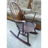An Ercol stained beech and elm framed open arm rocking chair with a high hoop and spindle back,