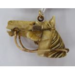 A carved ivory and yellow metal horses head pendant 11