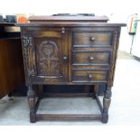 A Jaycee stained oak cupboard with a carved panelled door and three drawers,