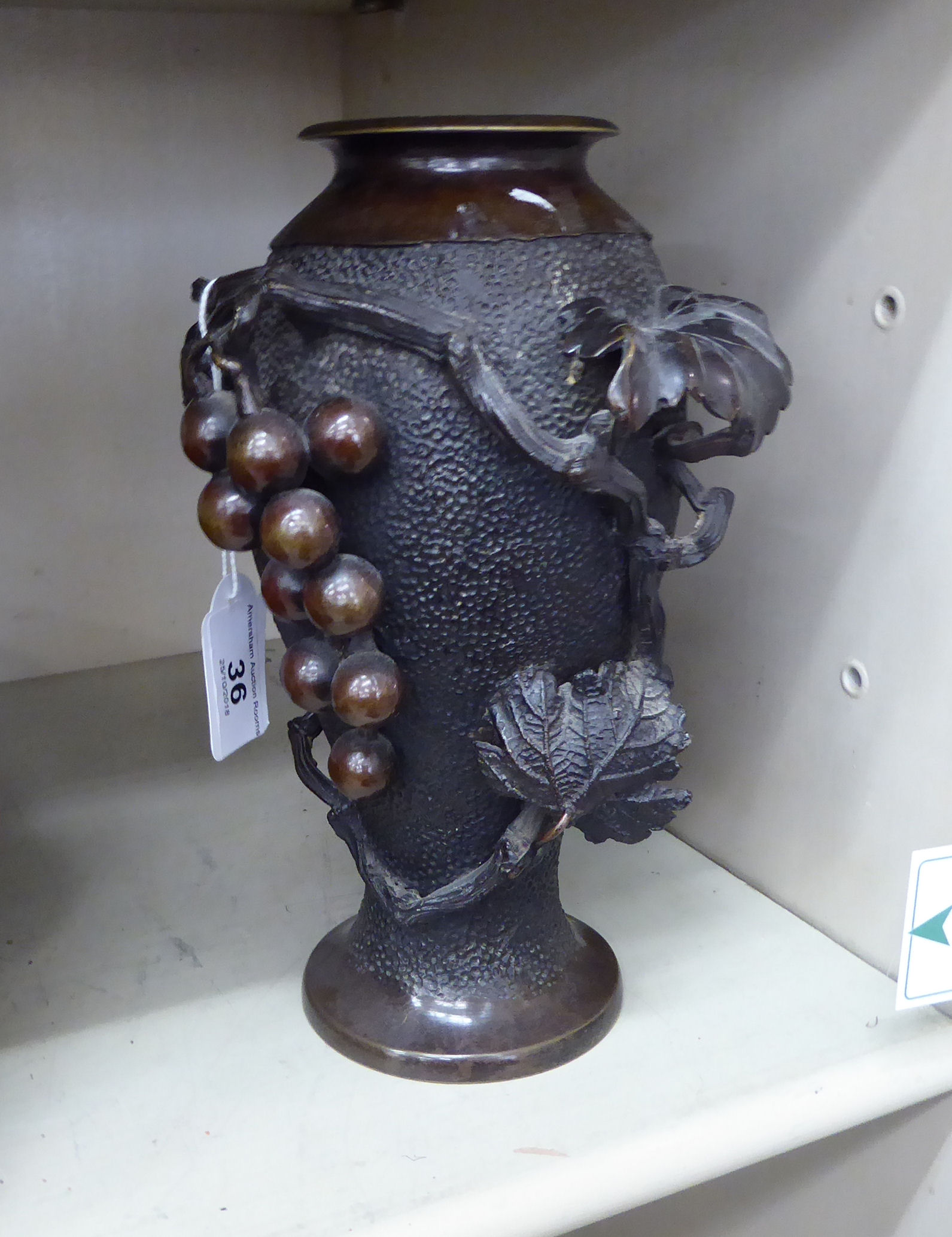 An early 20thC Japanese cast bronze vase of tapered form, decorated in relief with fruiting vines,