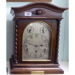 An early 20thC oak cased bracket clock with a low, round arched top,