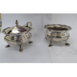 A silver lidded mustard pot with a loop handle and a wavy border,