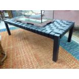 A Ralph Lauren coffee table, the black hide strapped top raised on square,