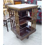 An early 20thC string and bone inlaid mahogany revolving two tier bookcase with slatted sides,