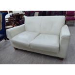 A modern two seater settee, upholstered in cream hide,