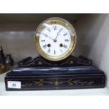 A 1930s black slate cased mantel timepiece; the movement faced by a white enamel Roman dial,