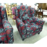 A pair of modern wingback armchairs, upholstered in bold poppy patterned fabric,