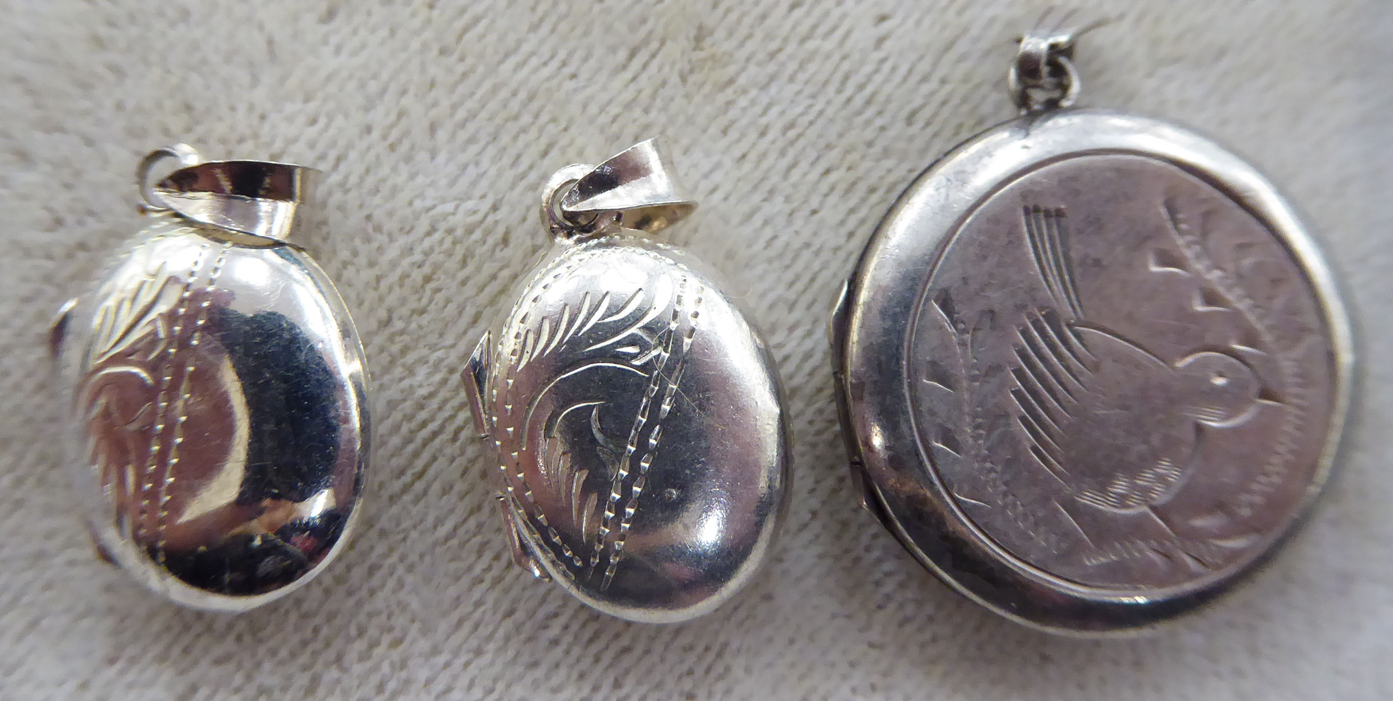 A pair of silver engraved miniature oval lockets;