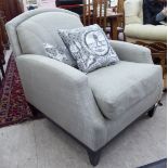 A modern beige fabric upholstered easy chair, raised on ebonised square,