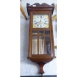 An early 20thC oak cased wall clock with a box pediment, over a full-height, glazed panelled door,