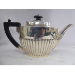 A silver teapot of oval, demi-reeded form with an angled spout, an ebonised handle and knop,