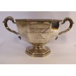 A silver trophy cup of octagonal form with opposing, foliate cast, C-scrolled handles,