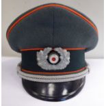 A German Army peaked cap, having red piping with a wreath emblem,