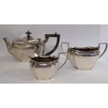 A three piece silver tea set of multi-panelled pedestal bowl design comprising a teapot with a