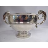 A silver trophy bowl with an embossed waistband and opposing hollow, C-scrolled handles,