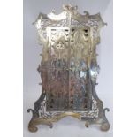 A white metal frame, ornately shaped, pierced and engraved with foliate scrolls and other ornament,