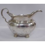 A silver milk jug of oval bulbous form with a cast C-scrolled handle and a ribbon tied wire rim,