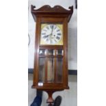 An early 20thC oak cased wall clock with a box pediment, over a full-height, glazed panelled door,