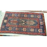 A Persian design rug with a central rectangular motif bordered by stylised designs on a red ground