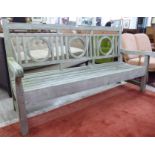 A modern teak framed garden bench, the railed, level, high back with circular motifs,