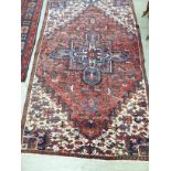 A Persian design rug with a central shaped motif bordered by stylised designs on a multi-coloured