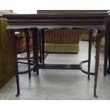 An Edwardian mahogany card table, the rotating, fold-over top enclosing a baize lined interior,