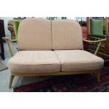 An Ercol light coloured beech framed Windsor hoop and spindle back settee, raised on short,