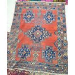 A Persian rug with five shaped motifs bordered by stylised designs on a red ground 62'' x 78''