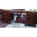 A modern mahogany finished partner's desk, having a tooled green hide scriber,