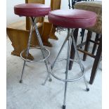 A pair of modern chromium plated tubular steel framed bar stools with red fabric upholstered,