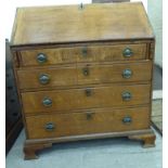 A George III honey coloured oak bureau with a fall-flap, over four graduated drawers,