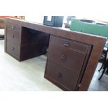 A modern stitched, simulated brown hide clad desk, raised on twin,