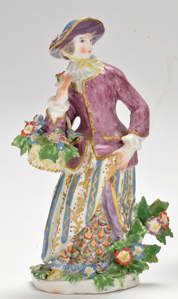 Bow figure of a flower girl, standing holding a basket of flowers over her right arm,