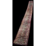 An extensive Sarough runner, with flowerhead decoration on red ground, 950 x 74cms.