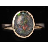 A black opal ring, the oval cabochon opal in collet setting on 9ct. yellow gold shank, ring size K.