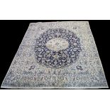 A Nain carpet, the central rosette surrounded by floral scrolls on blue ground, 345 x 243cms.