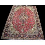 A Tabriz style carpet, the central medallion and flowers of geometric form on claret ground,