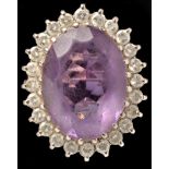 An amethyst and diamond cluster ring, the oval facet cut amethyst measuring 19.9 x 14.