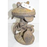 A Yoruba carved wooden divination bowl, on a base depicting a man with shield.