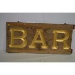 A gold painted wooden "Bar" sign, 87 x 40cms.