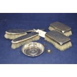 Four silver backed hairbrushes; a pin dish inset Persian coin;