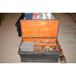A black painted joiner's tool chest containing an assortment of hand tools and sundry containers.