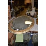 An oval bevelled mirror in painted frame.