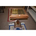 A 20th Century oak games table, the chequerboard top lifting to reveal chess and draughts under,