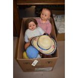 Assorted dolls and outfits in a box.