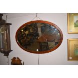 An Edwardian inlaid oval bevel plate mirror, 90cms wide.