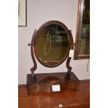 A mahogany swing toilet mirror, with oval plate and serpentine base.