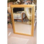 A modern bevelled rectangular wall mirror in gold coloured frame.