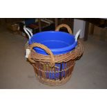 A large wicker log basket; and a blue plastic bucket.